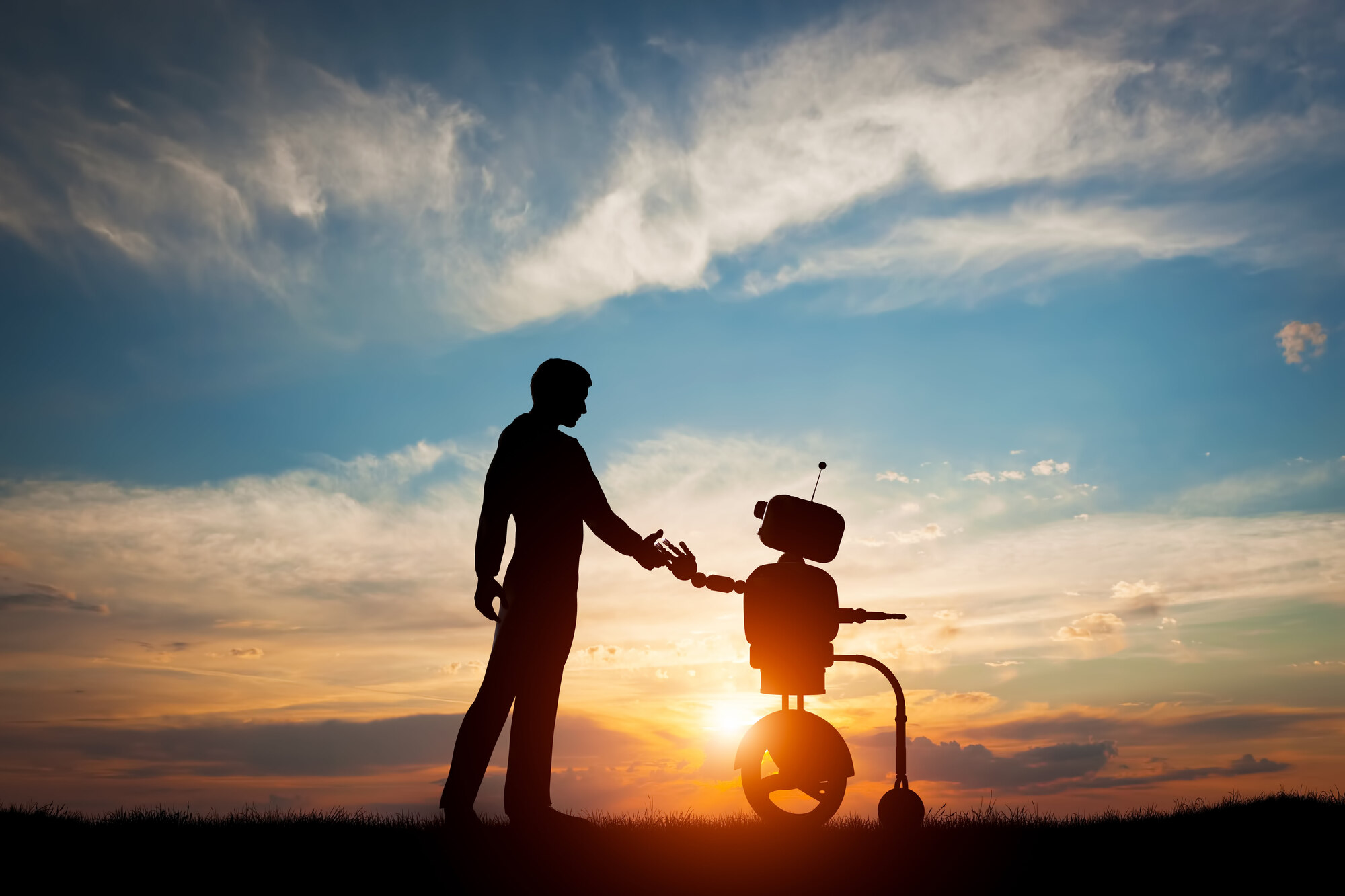 איש ורובוט אוחזים ידיים בשקיעה